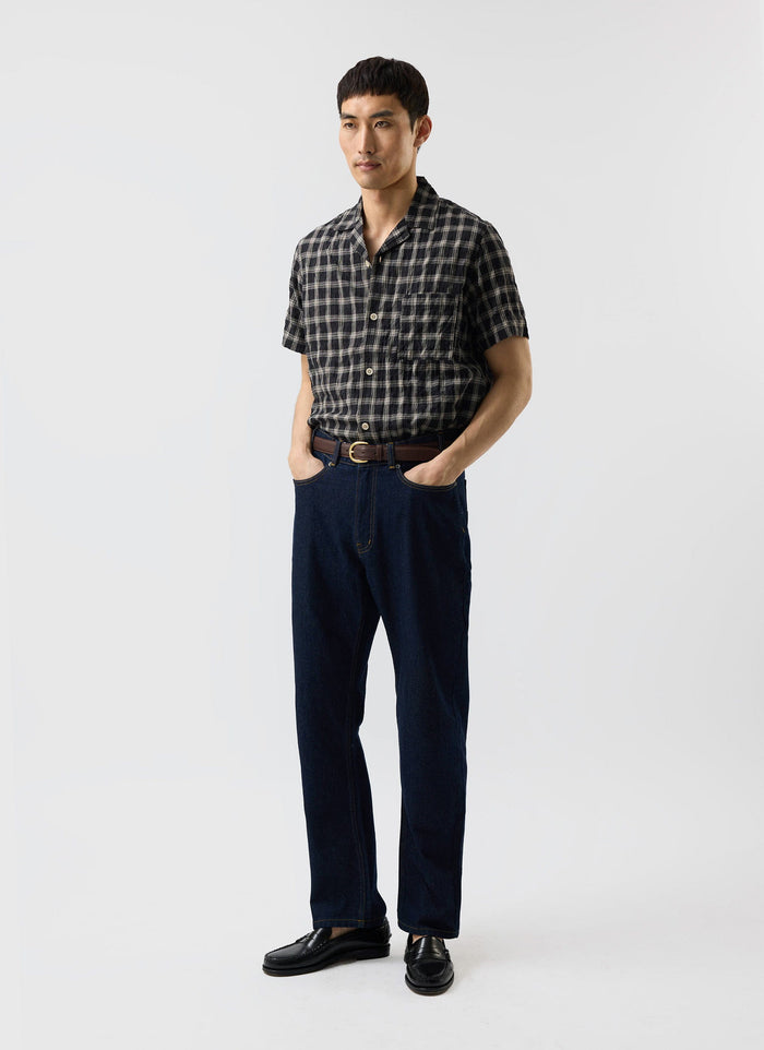A model wears the Percival Ryco Cuban Collar Shirt in black and white check, paired with dark denim jeans and black loafers.