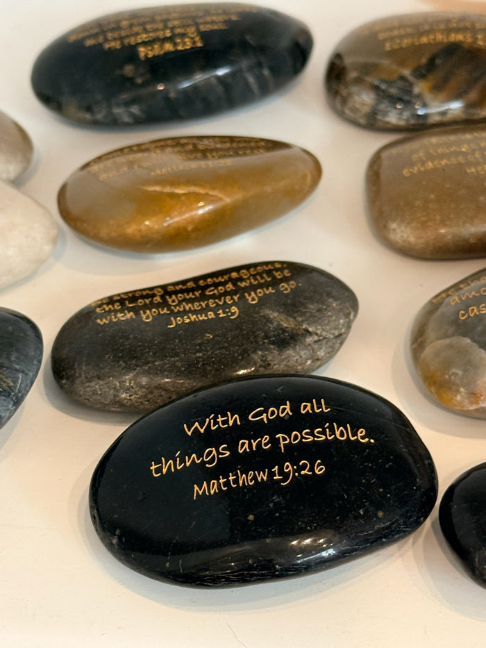 Decorative stones with engraved text on a white surface