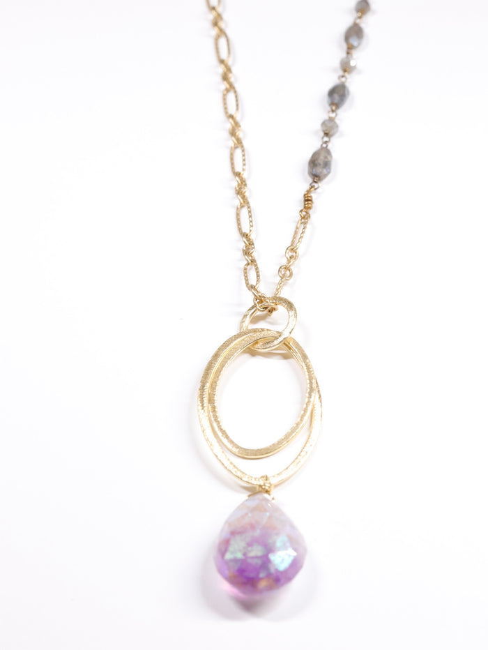 Close-up of gold and labradorite chain necklace with hammered oval rings and faceted amethyst teardrop pendant on white background.