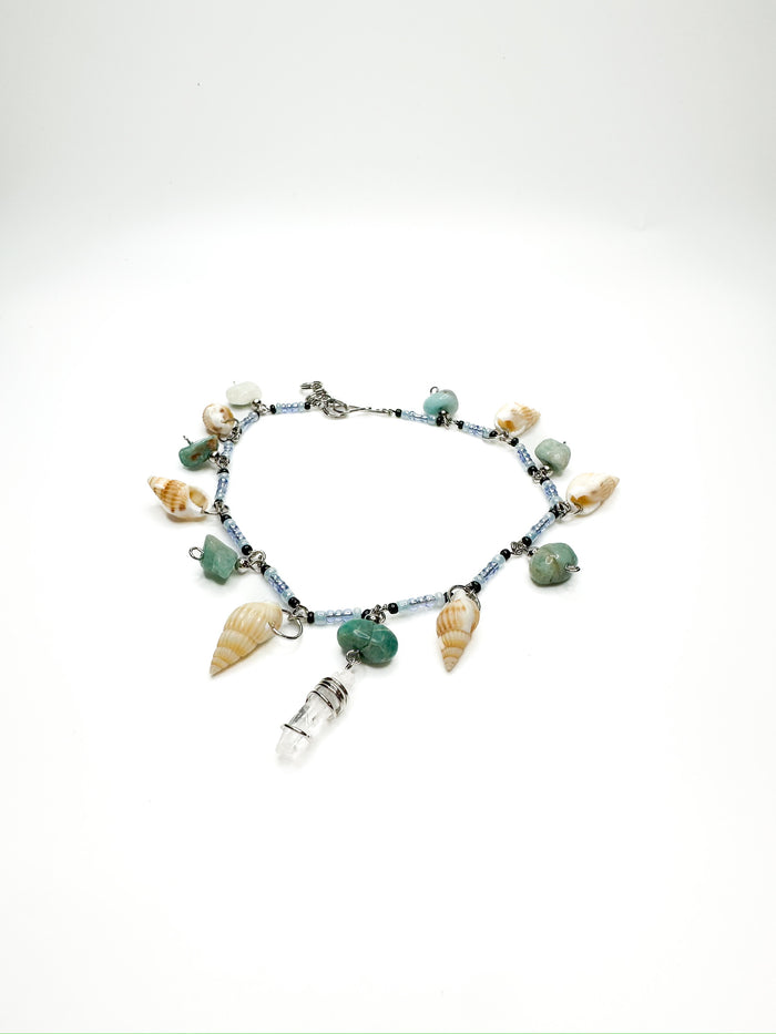Beaded anklet with hanging seashells, green gemstones, and a clear quartz charm