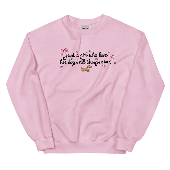 The Sassy Woof Sweatshirt - Just A Girl is a light pink, pre-shrunk top featuring "Just a girl who loves her dog & all things pink" with hearts, stars, a bow, and a cartoon dachshund beneath the text.