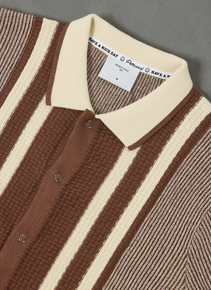 A close-up of the Percival Teramo Knitted Polo Shirt in ecru and brown stripes, highlighting the textured knit and collar.