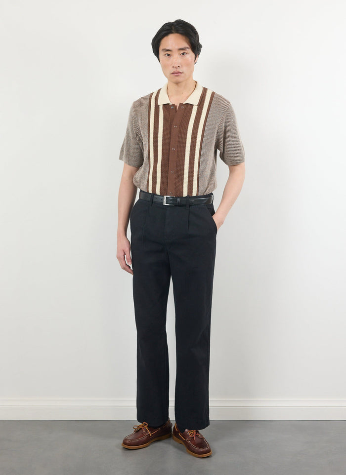 A model wears the Percival Teramo Knitted Polo Shirt in ecru, styled with black trousers against a white background.