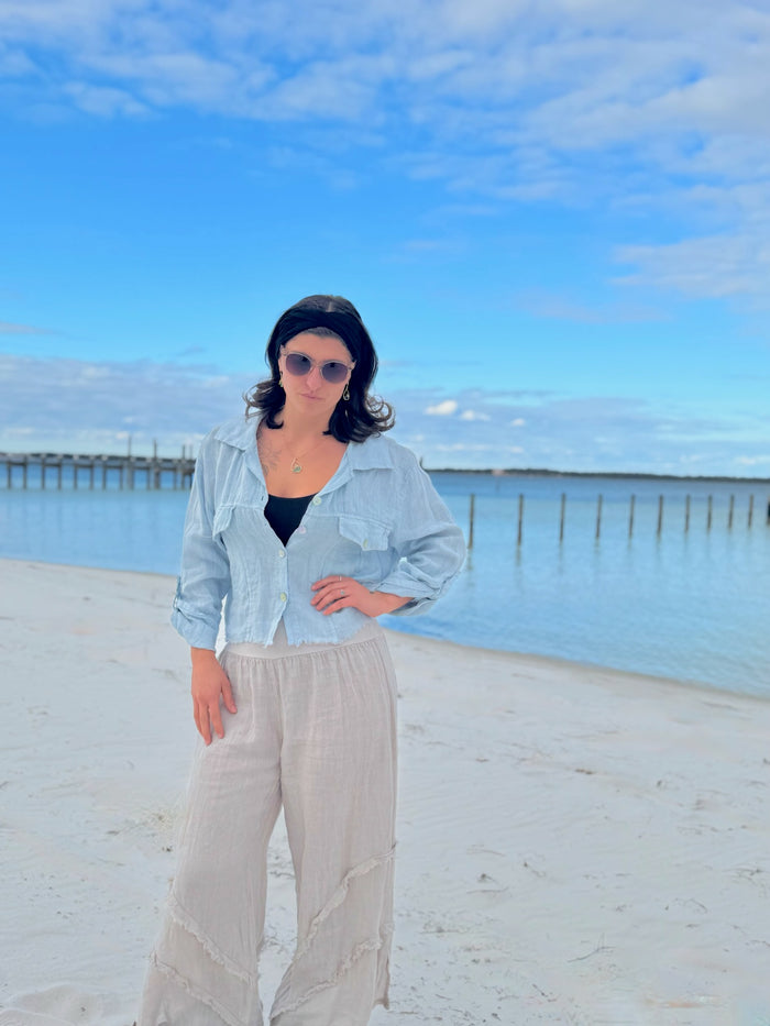 Person standing on a beach with a blue sky and ocean in the background