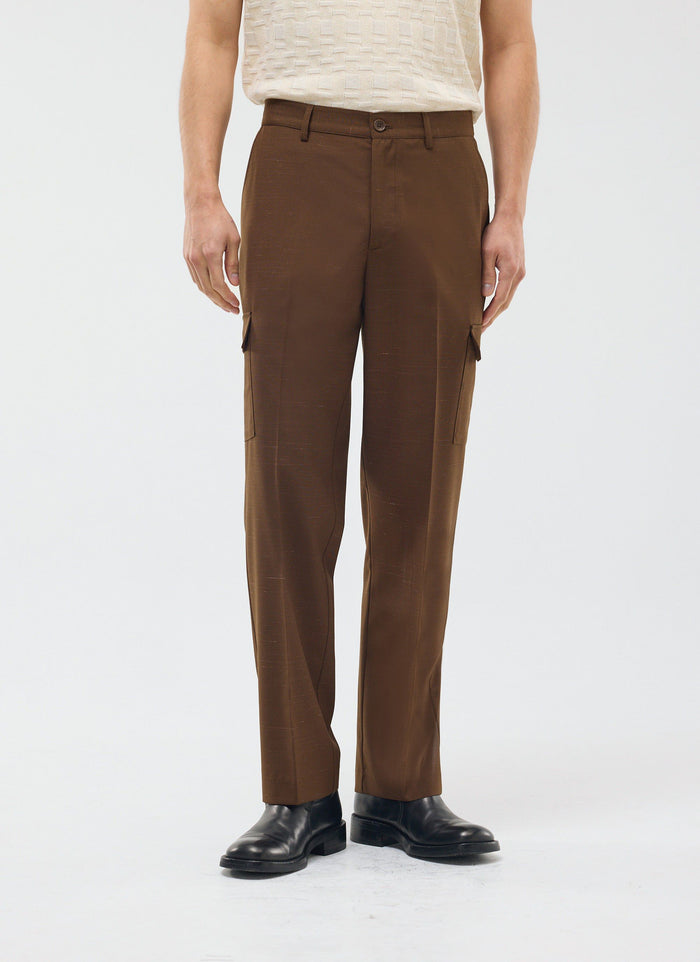 A model wears the brown Percival Trentino Tailored Patch Pocket Trousers with a cream textured top and black leather shoes.
