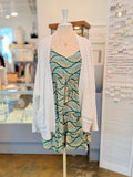 The Trina Dress in Tropical Green styled with cozy white knit cardigan and gold necklace for a layered spring look