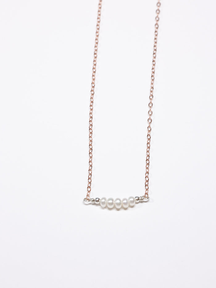 Rose gold chain necklace featuring a horizontal row of five small white pearls, spaced with silver accents, displayed on a white background.