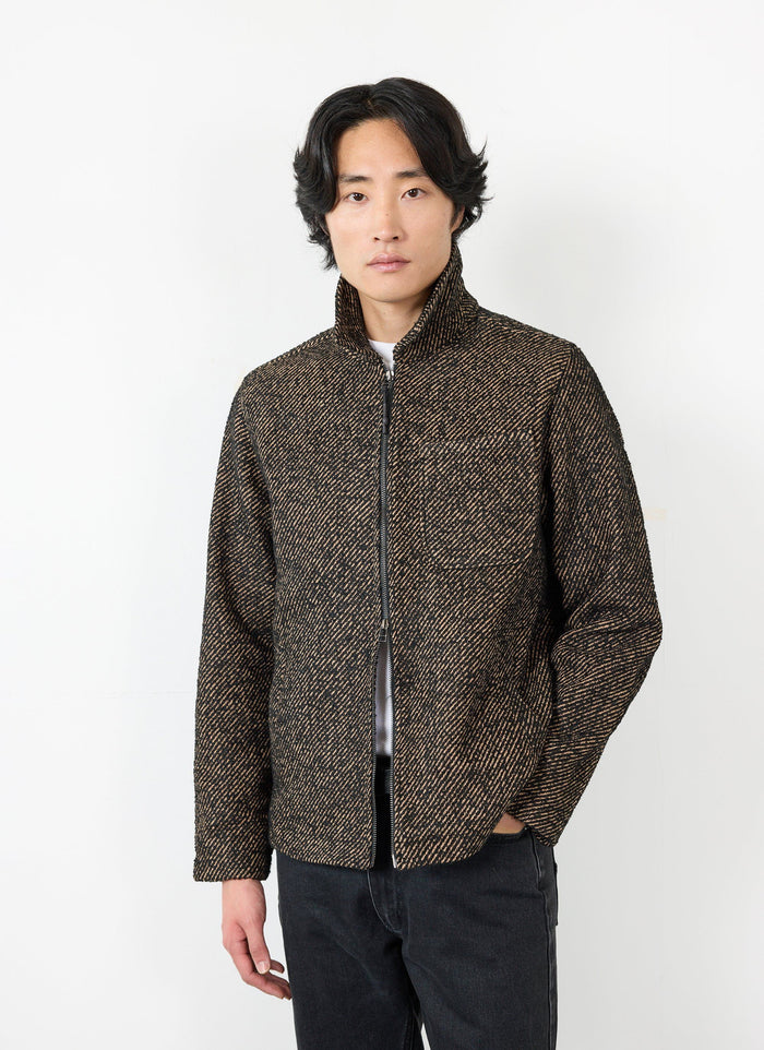 A model wears the Percival Zip Overshirt in Oak, a textured black and brown twill jacket with a front zip.