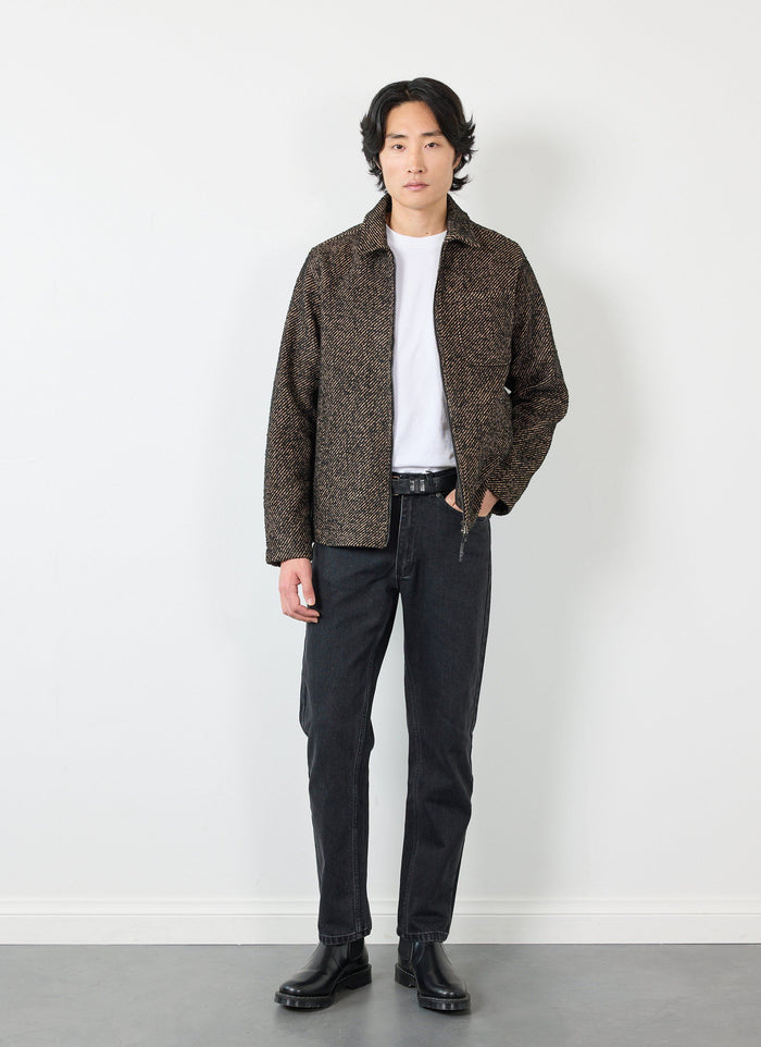 A model wears the Percival Zip Overshirt in Oak twill, layered over a white t-shirt with black jeans and black boots.